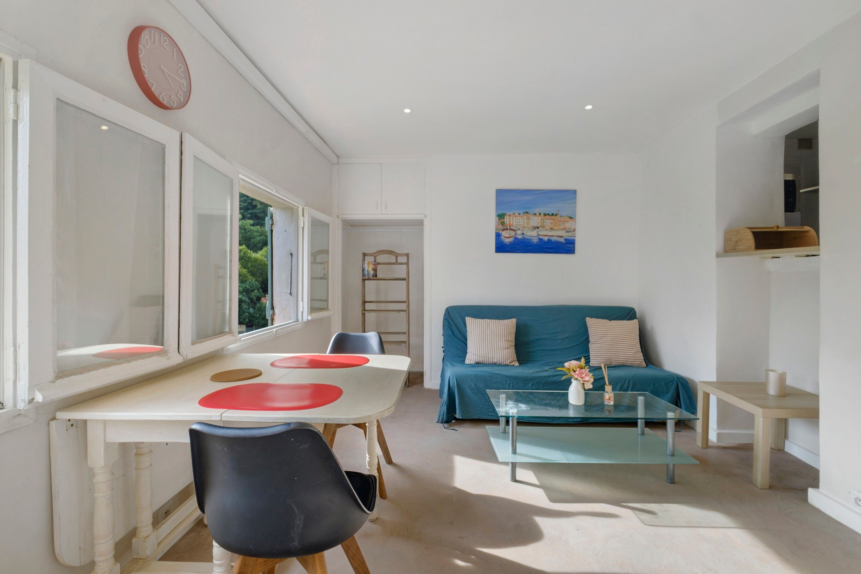 Una habitación con una mesa de comedor, un sofá, una mesa baja de vidrio y un cuadro en la pared.