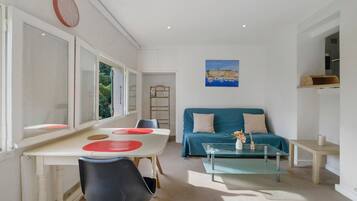 Una habitación con una mesa de comedor, un sofá, una mesa baja de vidrio y un cuadro en la pared.