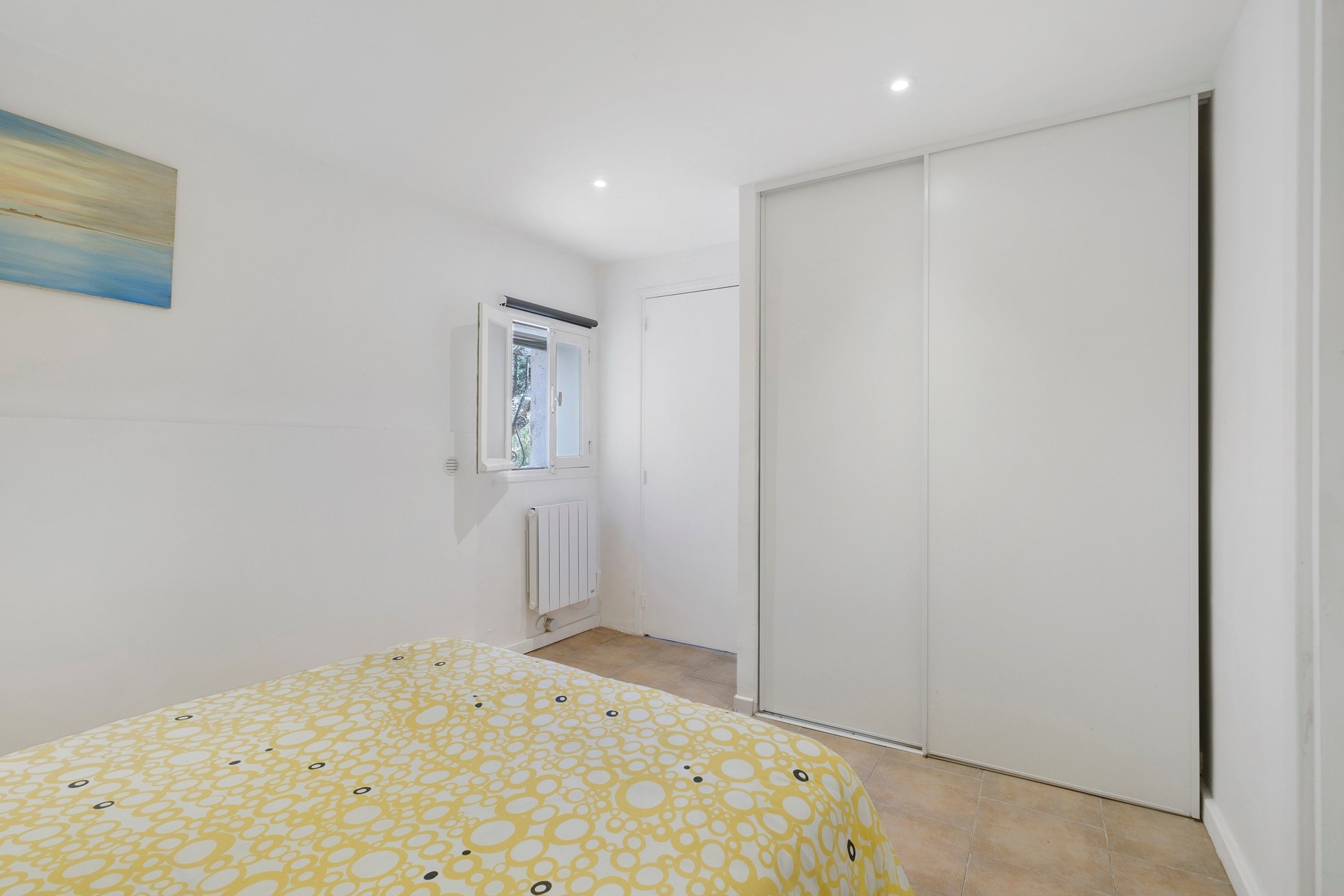 Ein Schlafzimmer mit einem Bett, einem Kleiderschrank, einem Heizkörper und einem Fenster.