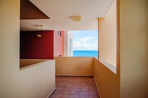 A narrow corridor with a view of the sea through an open door. - Ocean View Condo with Pool Near El Combate Beach (Boquerón)