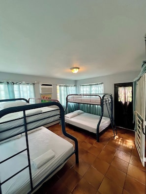 Ein Schlafsaalzimmer mit Etagenbetten, einer Heizung und einem Fenster mit Vorhängen.