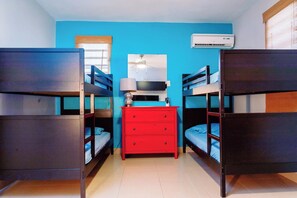 Ein Zimmer mit Etagenbetten, einem roten Schminktisch, einem Deckenventilator und einer Klimaanlage.