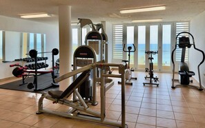 Ein Fitnessstudio mit verschiedenen Trainingsgeräten, darunter ein Squat-Rack, Kurzhanteln und ein Laufband.