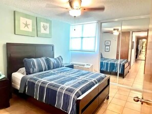 A bedroom with a bed, a nightstand, a ceiling fan, a window, and a mirror. - Beachside Condo with Pool and Ocean Views (Pole Ojea)