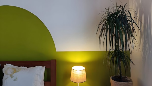 A bedroom with a bed, bedside lamp, nightstand, and a potted plant. - Apartment 'Casa Oliveira' with Mountain View, Wi-Fi and Air Conditioning (Melides)