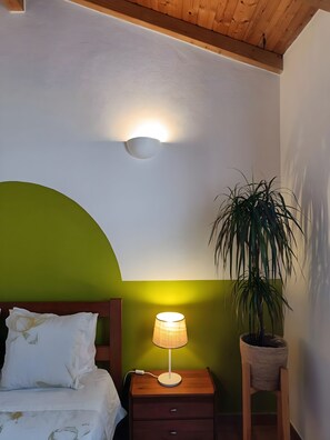 Un dormitori amb llit, una làmpada de nit, una tauleta de nit i una planta en test.