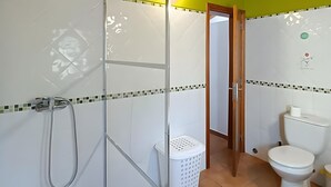 A bathroom with a shower, toilet, and a visible door leading to another room. - Apartment 'Casa Oliveira' with Mountain View, Wi-Fi and Air Conditioning (Melides)