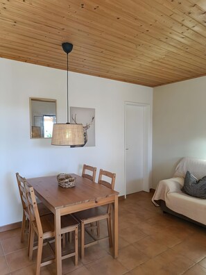 Ein Essbereich mit einem Holztisch, Stühlen, einer Hängelampe und einem Wandspiegel.