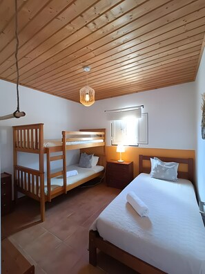 Ein Zimmer mit einem Etagenbett, einem Einzelbett, einem Nachttisch mit Lampe und einer Hängeleuchte.