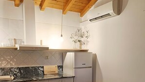 A modern kitchen with a built-in stove, a refrigerator, and a dining area with a sofa and cushions. - Apartment 'Casa Medronheiro' with Mountain View, Wi-Fi and Air Conditioning (Melides)