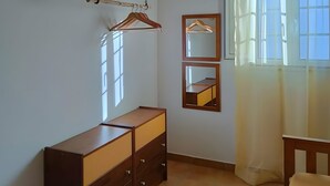 Habitació amb sostre de fusta, un taulell de nit de fusta, un mirall i una finestra amb cortines.