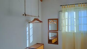 Una habitación con techo y aparador de madera, un espejo y una ventana con cortinas.
