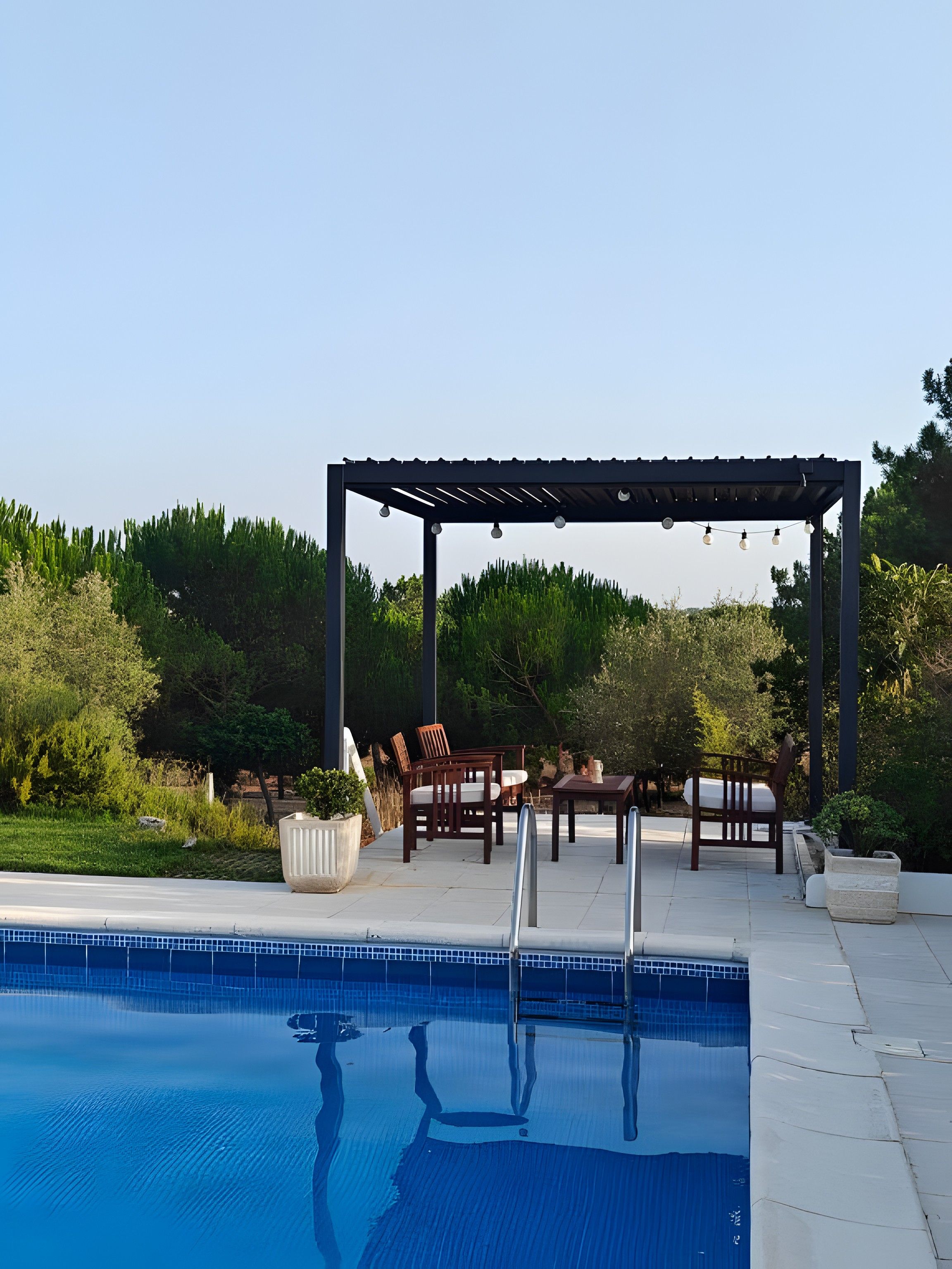 A swimming pool with a pergola and outdoor furniture.