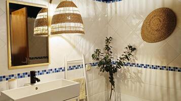 A bathroom with a wooden ceiling, a white sink, a mirror, and a blue-tiled wall.