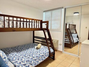 A bedroom with a bunk bed, a small bedside table, and a mirror. - Family-Friendly | Year-Round Pool & Beach Nearby (Boquerón)
