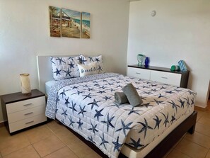 Une chambre à coucher comprenant un lit, des tables de chevet, une commode et un mur décoré d’œuvres d’art.