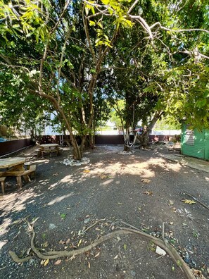 Shaded outdoor seating tucked under mature trees — a cool, peaceful retreat. - Near Beach Stay | Pool Access, Tennis & Games (Boquerón)
