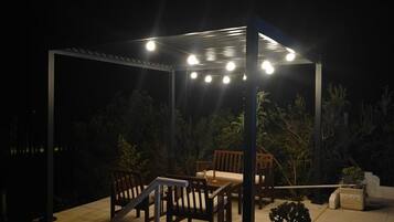 An outdoor patio area with a pergola, seating, and potted plants.