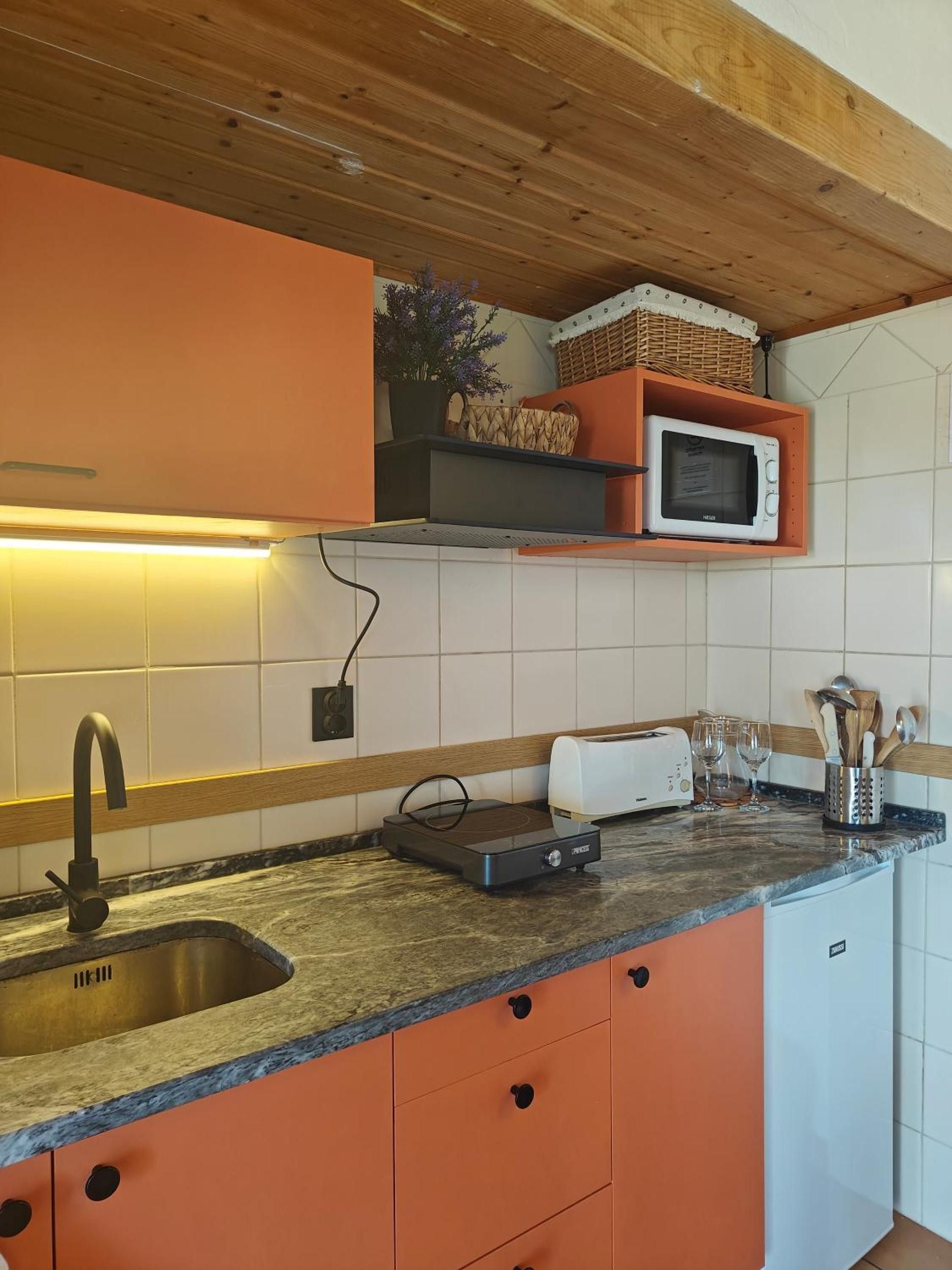 Uma cozinha com pia, micro-ondas, torradeira e bancada com torradeira e copos.