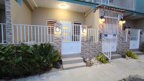 A residential building with a stone facade, white doors, and a gated entrance. - Family-Friendly Condo Near Beach and Nightlife (Boquerón)