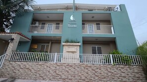 A multi-story building with balconies, a central entrance, and a sign indicating it is a condominium named 'El Velero'. - Family-Friendly Condo Near Beach and Nightlife (Boquerón)