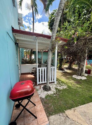 A covered outdoor seating area with a barbecue grill, surrounded by palm trees and a small garden. - Coastal Stay Near Beach w/ Pool Access and Patio (Boquerón)