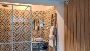 Un baño con ducha, lavamanos y pared de paneles de madera.