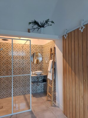 A bathroom with a shower, a sink, and a wooden panel wall. - Apartment 'Casinha De Lume' with Mountain View, Wi-Fi and Air Conditioning (Melides)