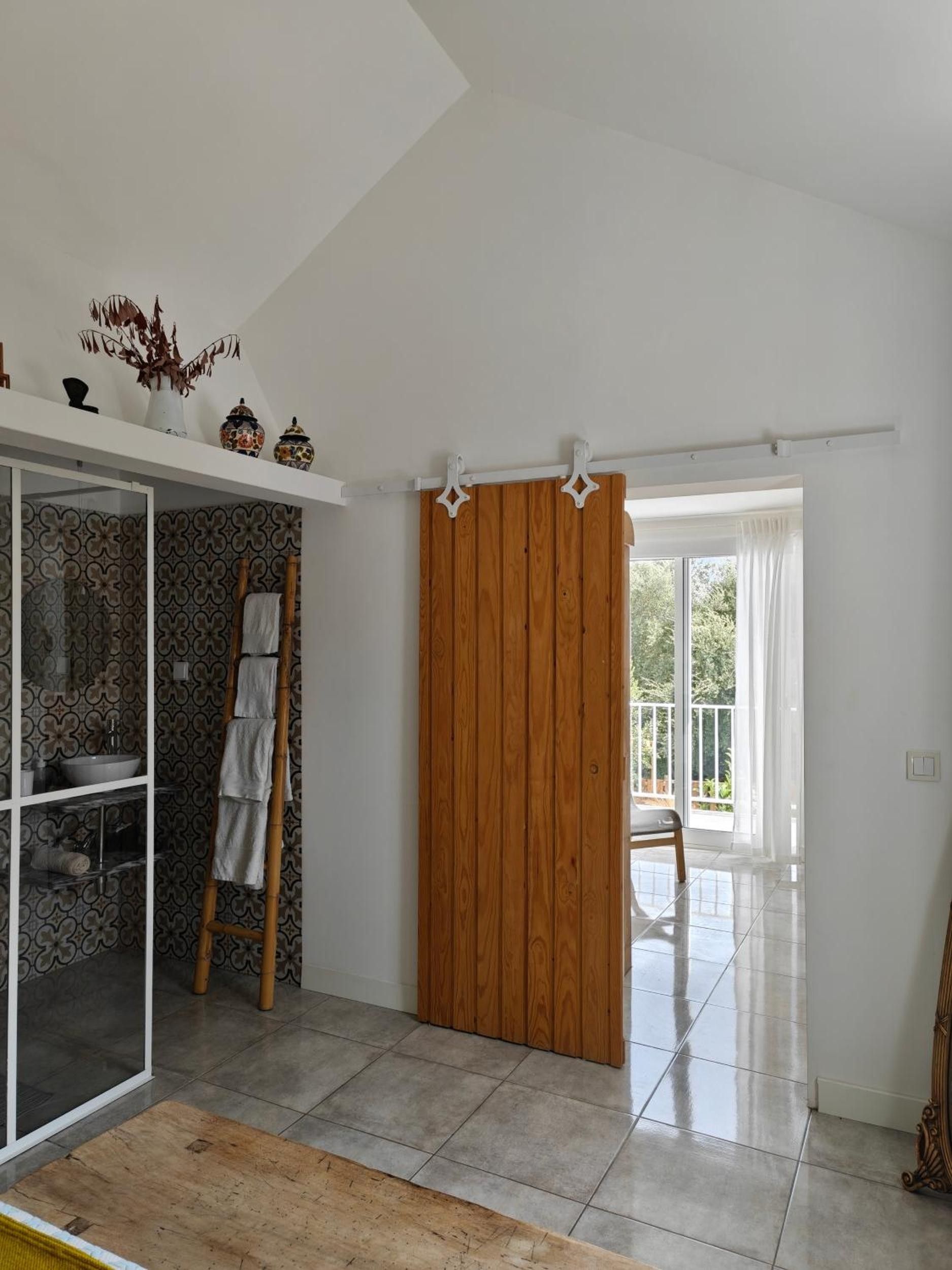 A room with a sliding wooden door, a glass shower enclosure, and a view of the outdoors.