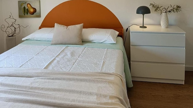 A bedroom with a bed, a nightstand, a lamp, and a wall decoration. - Apartment 'Loft Vale De Mouro' with Mountain View, Wi-Fi and Air Conditioning (Melides)