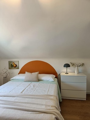 Un dormitorio con una cama, una mesita de noche, una lámpara y una decoración en la pared.