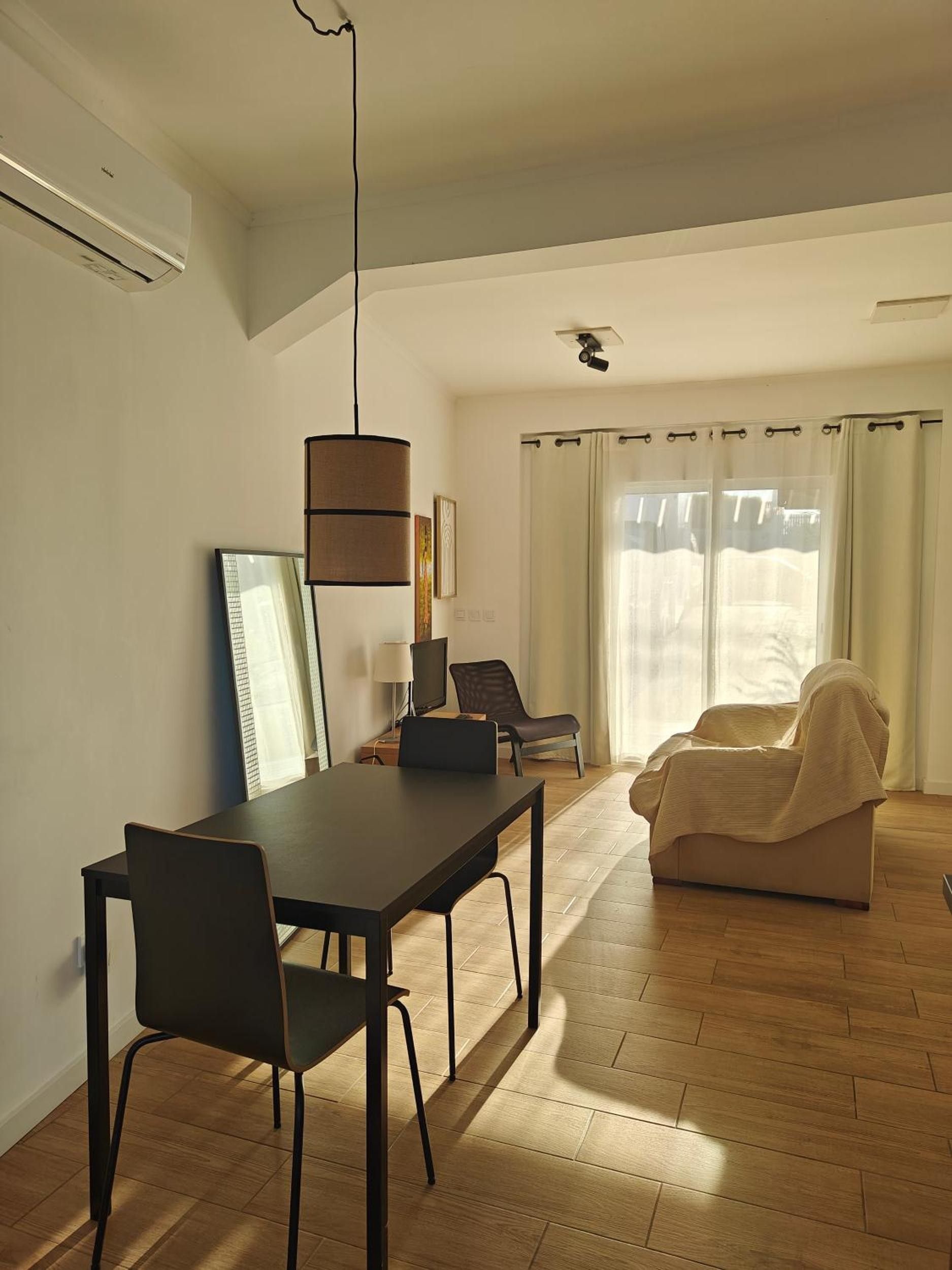 Un salon moderne avec un coin repas, comprenant un canapé, une table et un téléviseur.