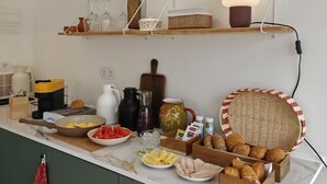A kitchen with a white countertop, various food items, a coffee maker, and a hanging light fixture. - Apartment 'Loft Vale De Mouro' with Mountain View, Wi-Fi and Air Conditioning (Melides)