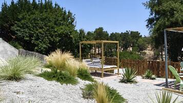 Un jardín con un porche de madera, suelo de grava y diversas plantas.