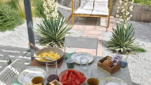 An outdoor dining area with a table set for breakfast, including bread, pastries, and fruit. - Apartment 'Loft Vale De Mouro' with Mountain View, Wi-Fi and Air Conditioning (Melides)