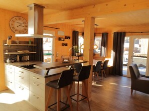Un interior de madera con cocina, comedor y taburetes de bar.