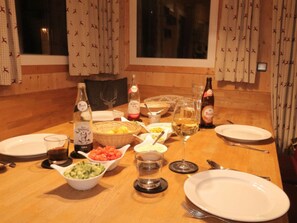 A dining table set with plates, bowls of food, glasses, and bottles of beverages. - One-bedroom Cabin (Sankt Georgen am Kreischberg)