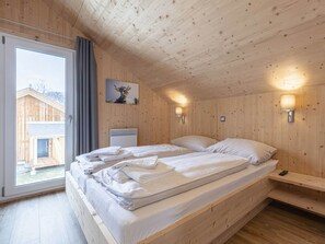 A wooden cabin room with a bed, a window, and a wall-mounted lamp. - One-bedroom Cabin (Sankt Georgen am Kreischberg)
