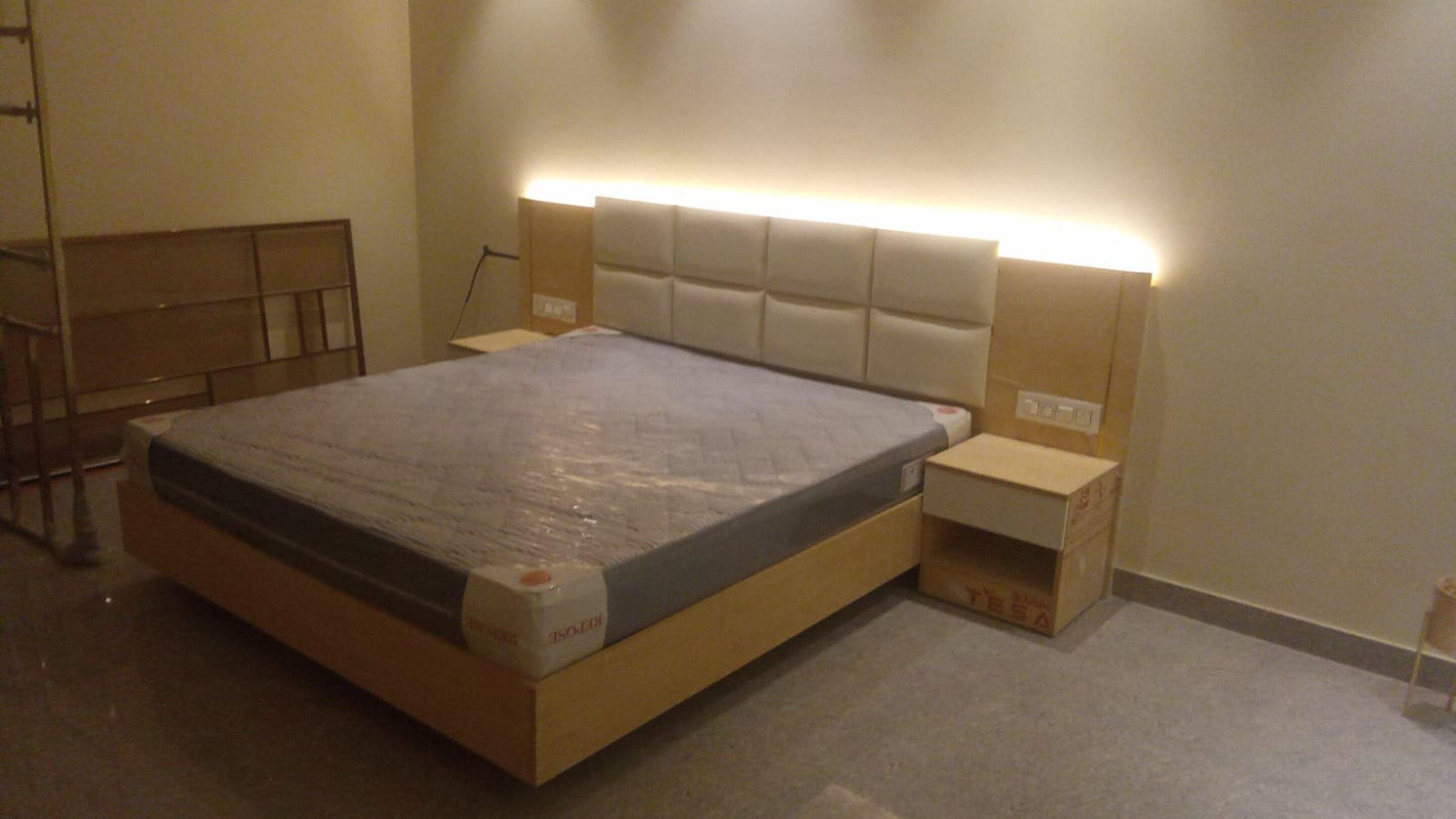 A bedroom with a bed, bedside tables, and a headboard with built-in lighting.