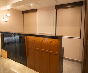 A reception area with a black counter, wooden paneling, and recessed lighting. - Suite Room Palette Hotel Whitefield (Bengaluru)