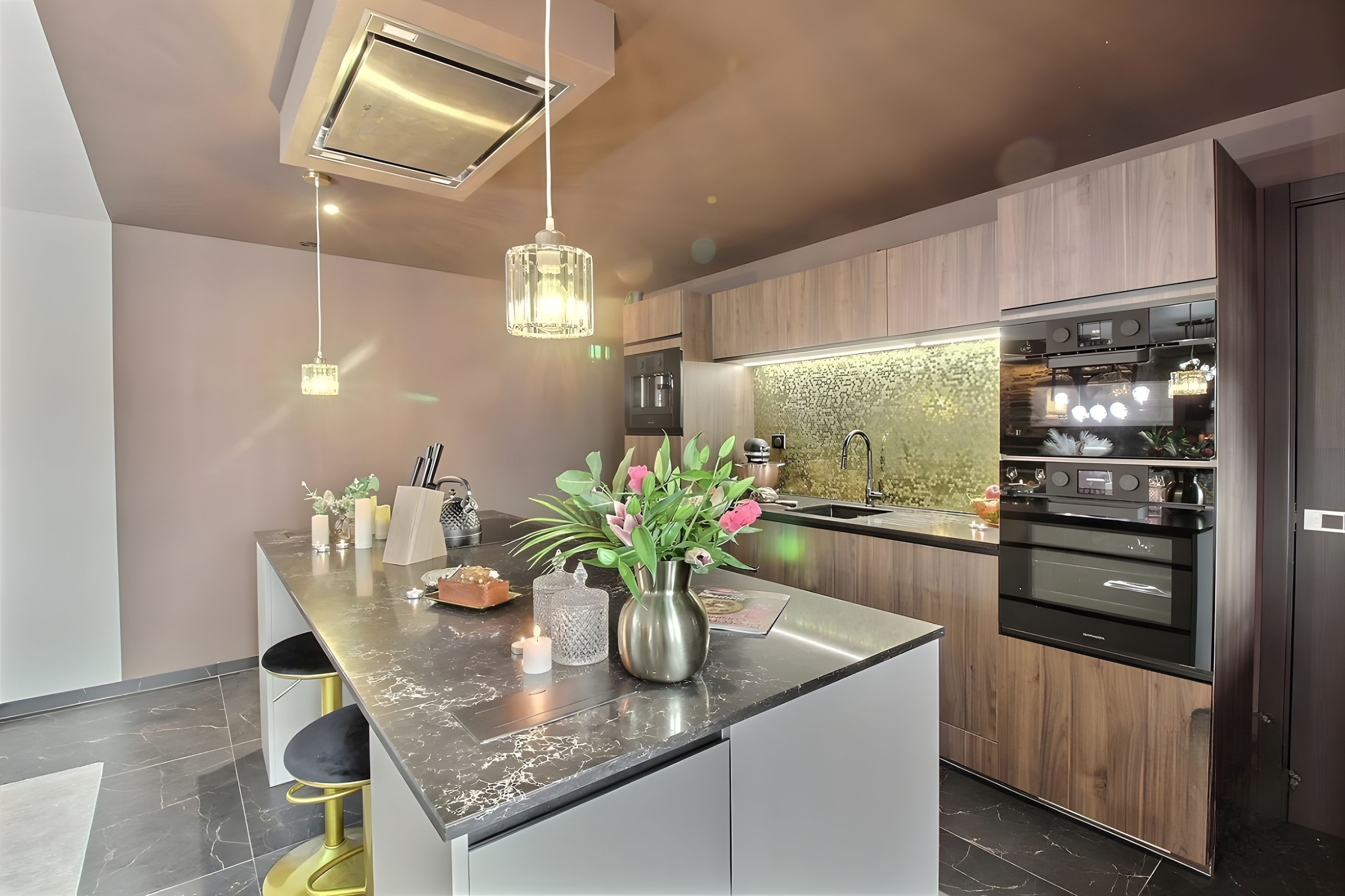 A modern kitchen with a central island, pendant lighting, and stainless steel appliances.