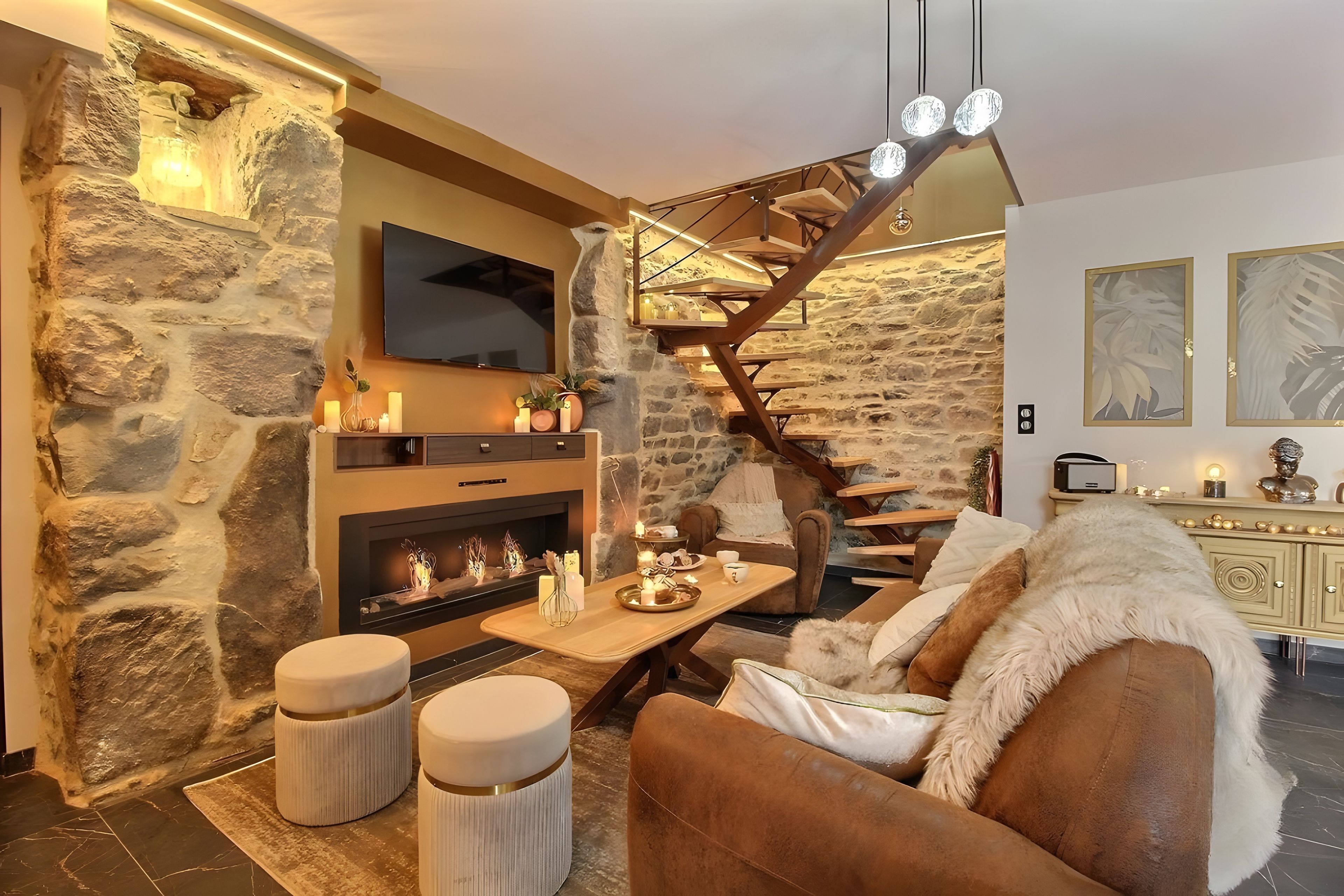 Ein gemütliches Wohnzimmer mit Steinwand, Kamin, einer Couch und einer Treppe.