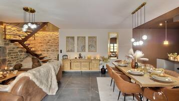 Un espace repas moderne avec un mur en pierre, un escalier en bois et une table à manger dressée pour quatre personnes.