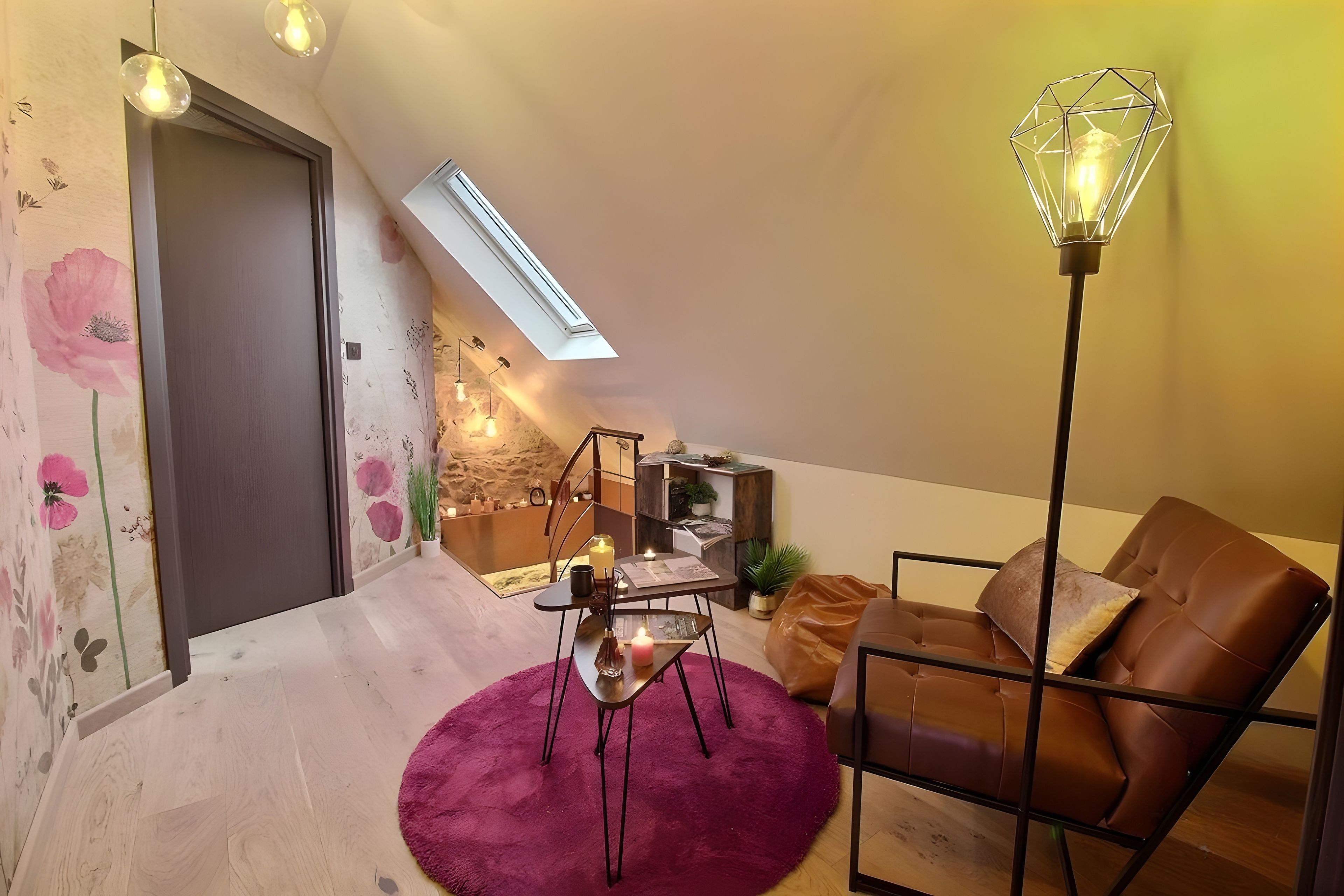 A loft-style living space with a sloped ceiling, a brown leather sofa, a glass coffee table, and a purple rug.