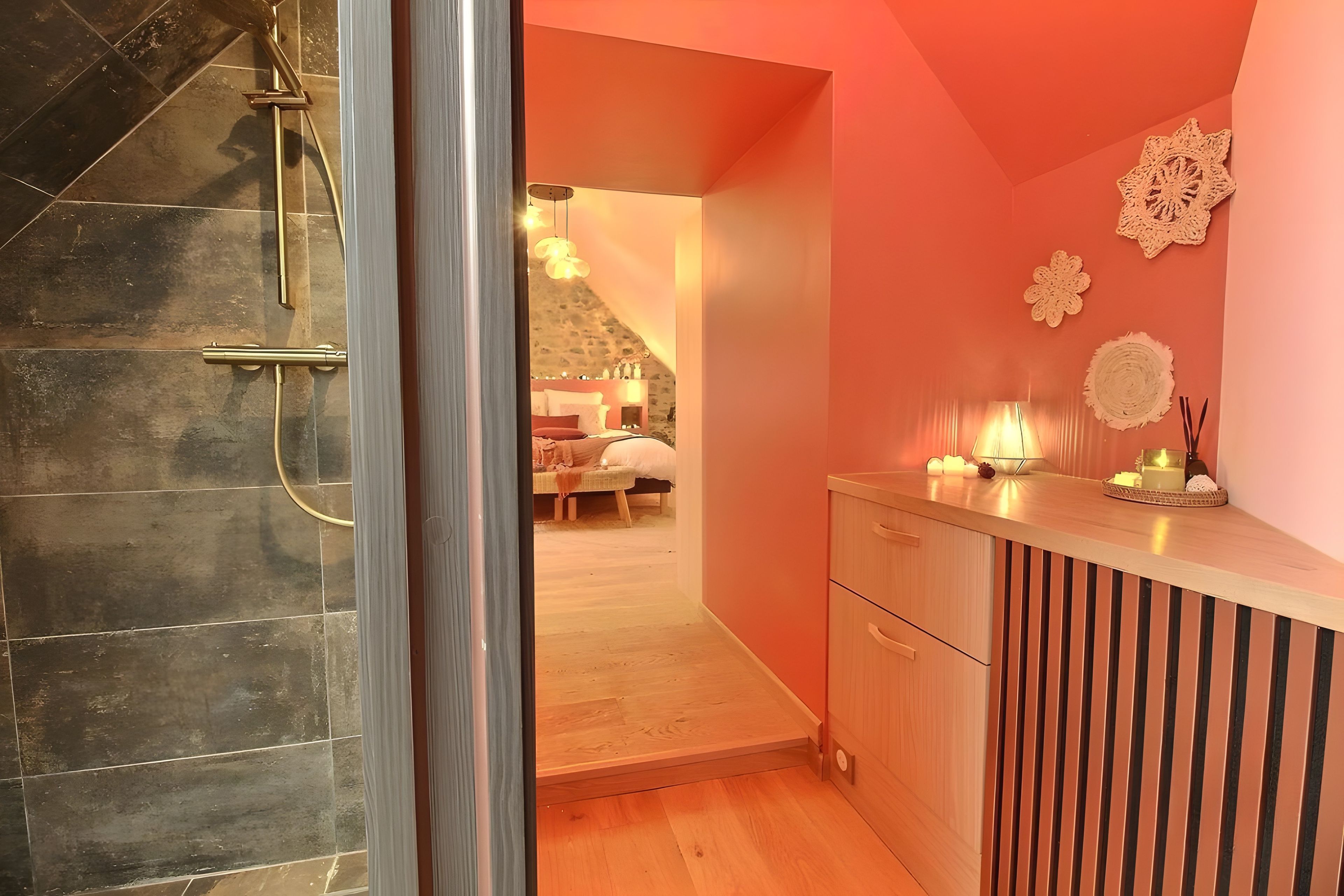 Une salle de bain moderne avec une douche, un meuble-lavabo en bois et une vue sur une chambre à coucher avec un lit et une table de chevet.