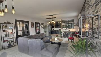 Ein modernes Wohnzimmer mit einer Eckcouch, einem Couchtisch und einem Essbereich mit einer Küche im Hintergrund.