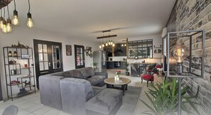 Ein modernes Wohnzimmer mit einer Eckcouch, einem Couchtisch und einem Essbereich mit einer Küche im Hintergrund.
