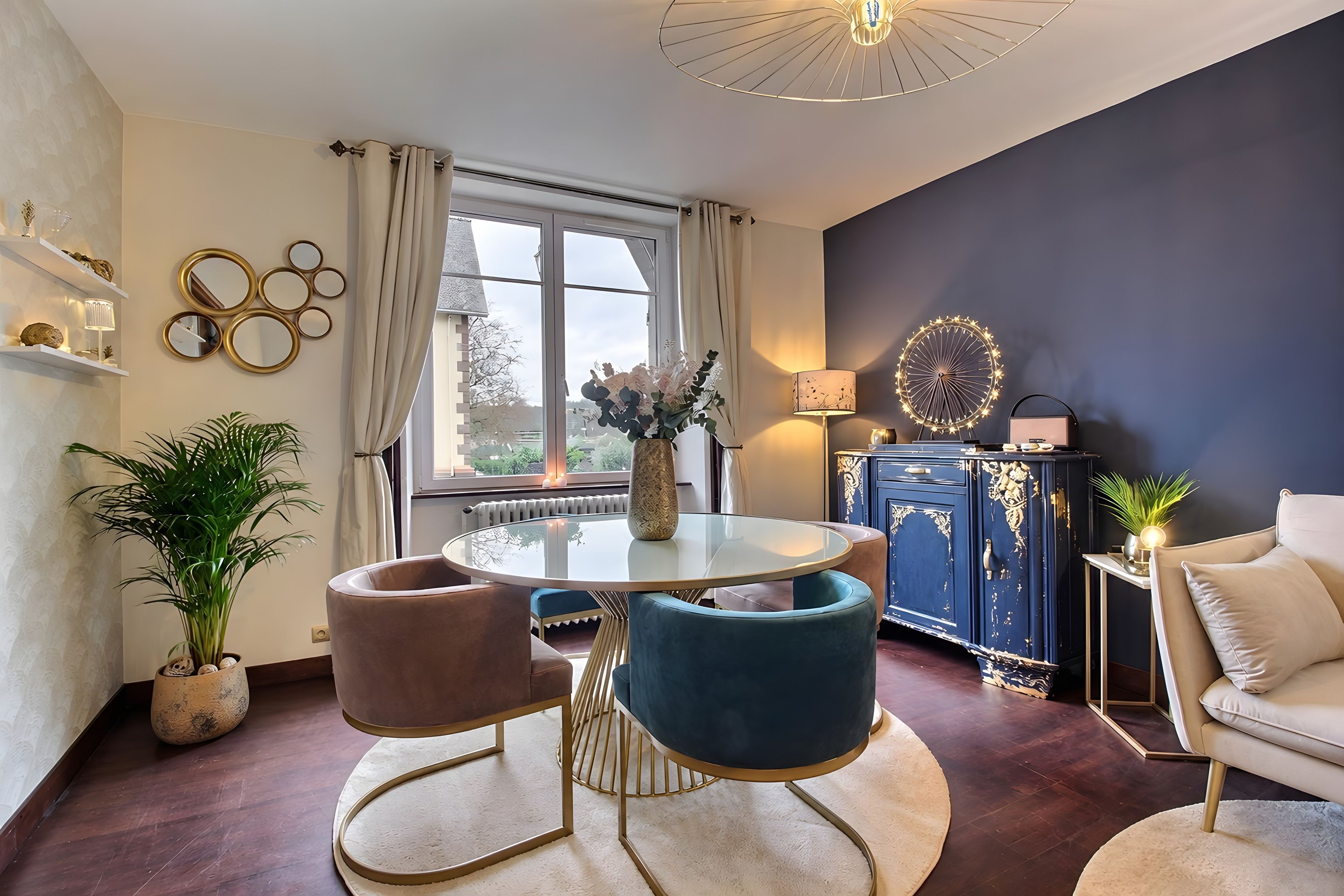 En moderne stue med et rundt glasbord, to stole, en sofa, et skab og en dekorativ lampe.