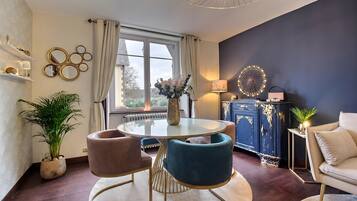En moderne stue med et rundt glasbord, to stole, en sofa, et skab og en dekorativ lampe.