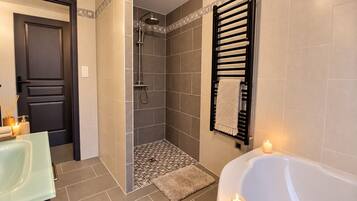 A modern bathroom with a shower, a bathtub, and a towel rack.